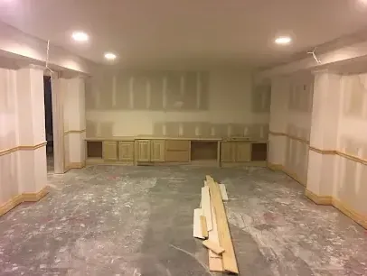 A finished basement room with the lower drywall cut away so the wall can dry