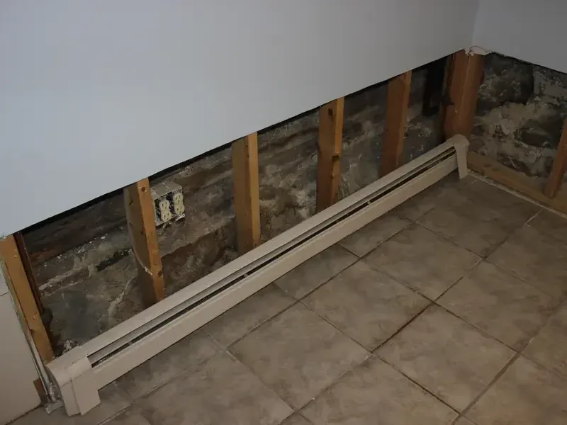 Lower drywall removed above a baseboard heater while the wall cavity dries
