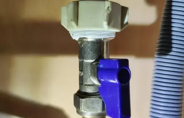 Supply valve and drain hose behind a washing machine in a laundry area