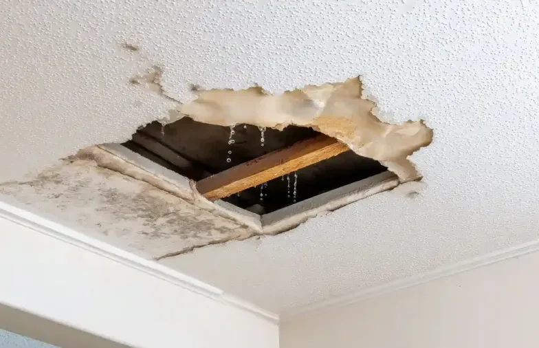 Water dripping through a broken ceiling under a roof leak