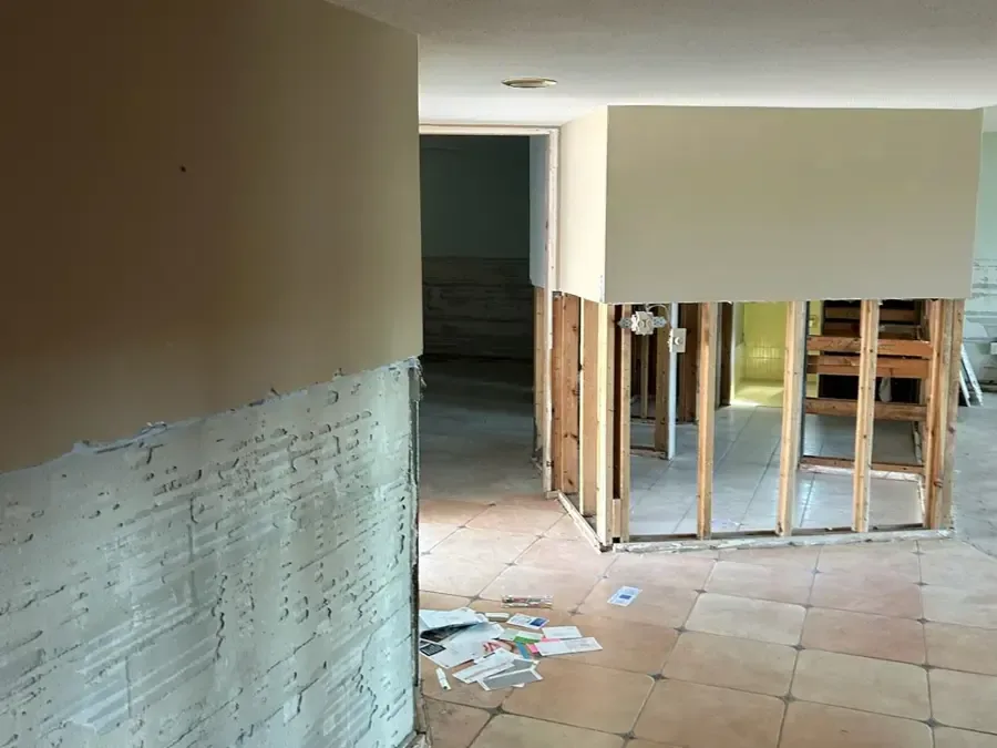 Flood-cut drywall and open wall framing above a tile floor during a dry-out